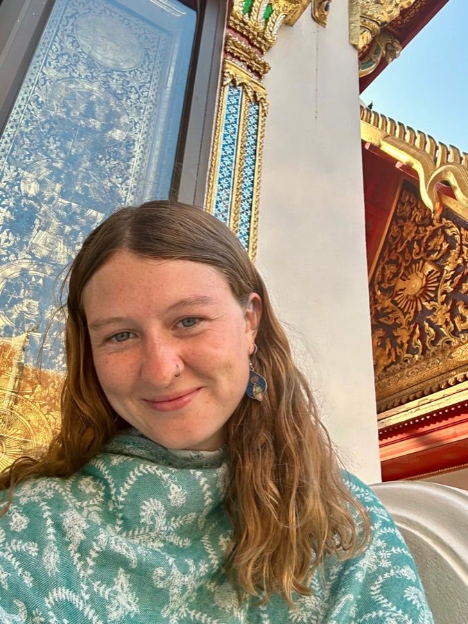 Lucy MacRae smiling, standing outside a gilded temple.